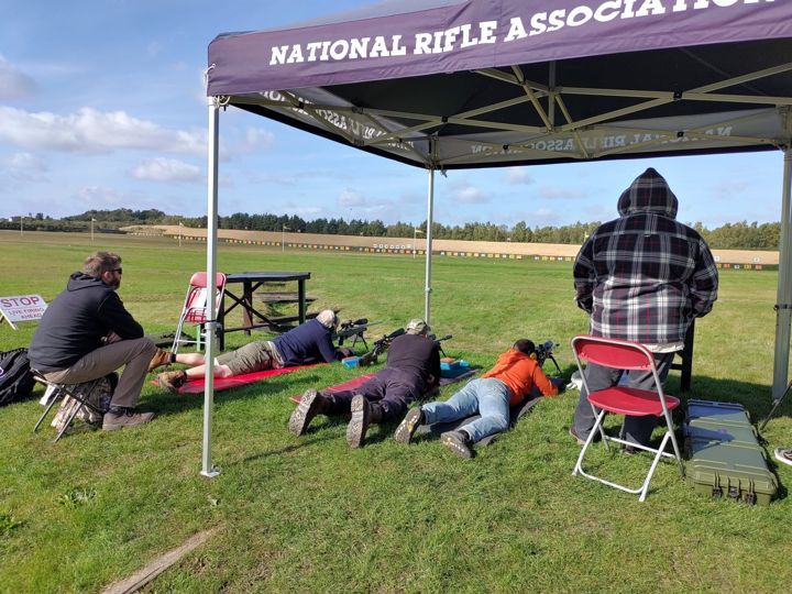 Members shooting under a National Rifle Association gazebo at Bisley