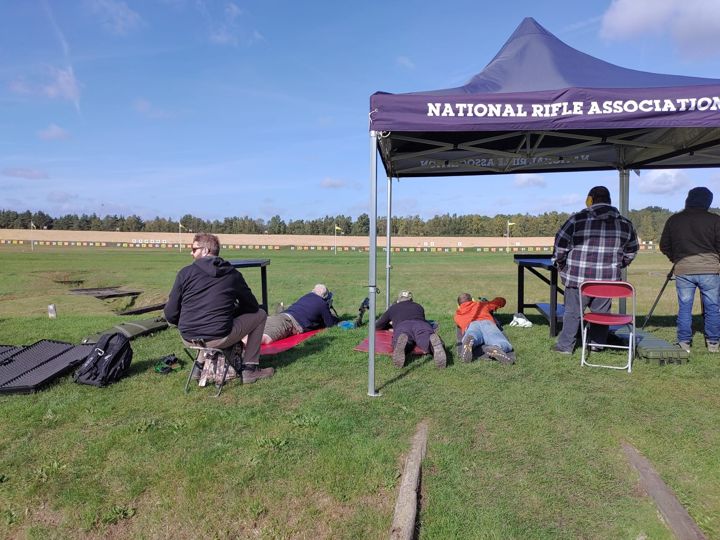 Members lying prone and seated under the National Rifle Association gazebo at Bisley