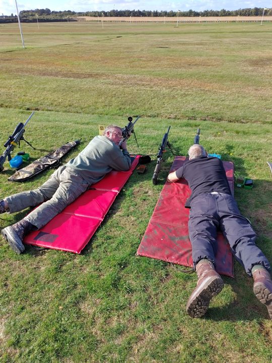 Two members lying prone on red mats at Bisley