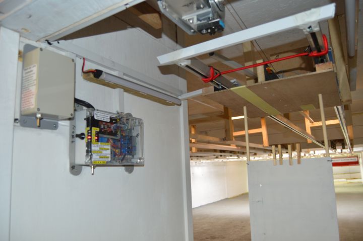 The electronic target retrieval equipment: a control box on the wall beside a lane, with the overhead track above